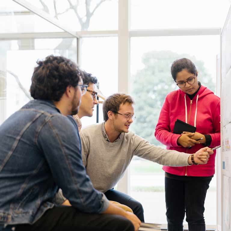 Students reviewing work that has been posted on a wall. 