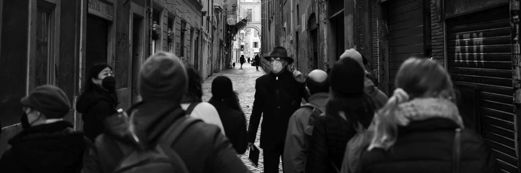 A black and white image of a person leading a group of students through the streets of Rome, Italy.