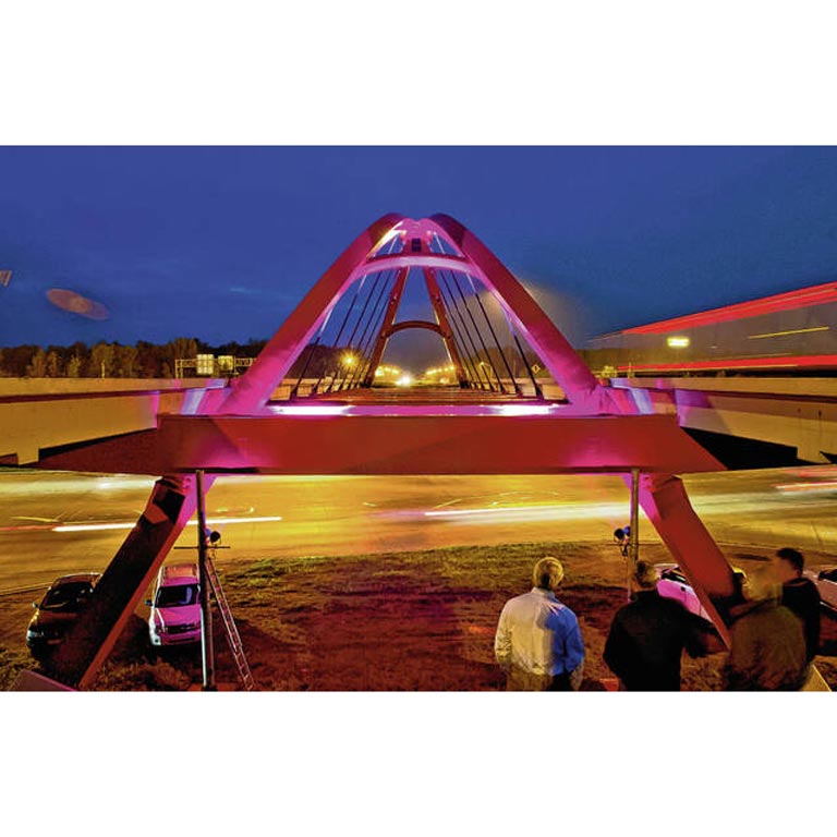 A long-exposure image of the red bridge in Columbus, Indiana lit at night by cars driving underneath it.